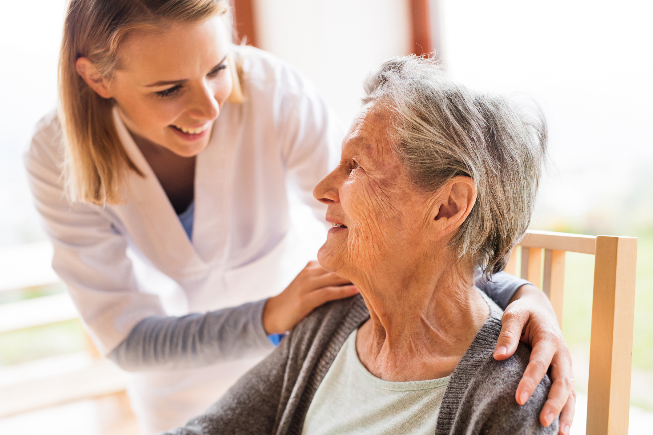 Health visitor and a senior woman during home visit. A nurse talking to an elderly woman.