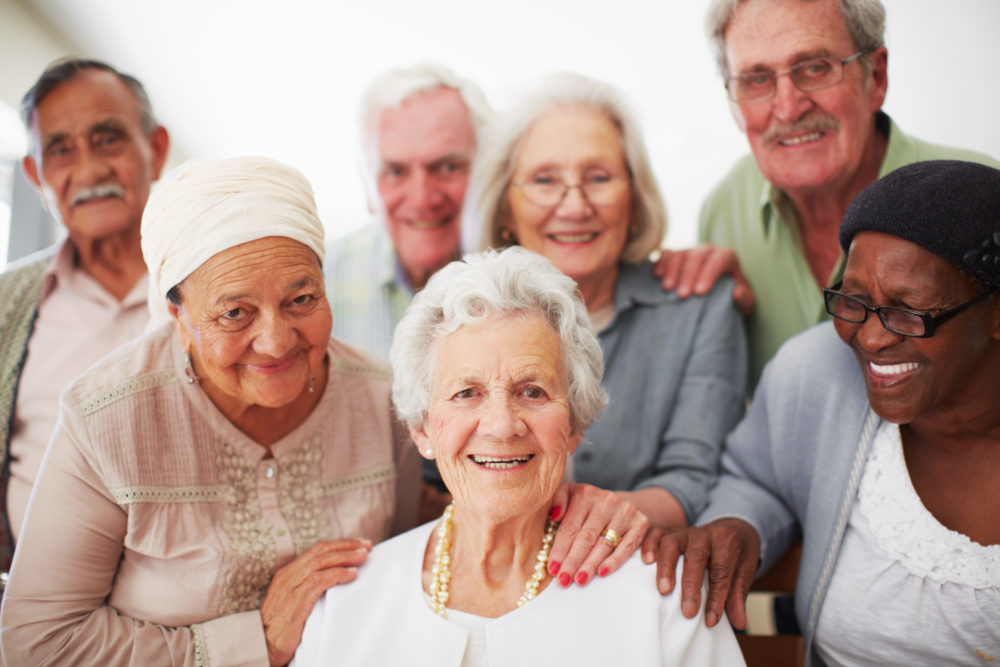 A group of seniors smiling together while in a retirement home